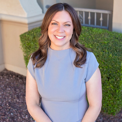 A woman in a blue shirt is smiling for the camera.