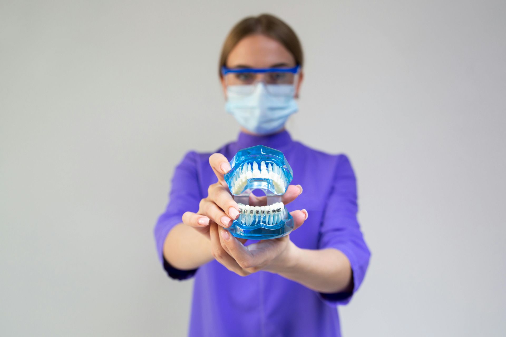 A woman is examining a man 's teeth in a dental office.
