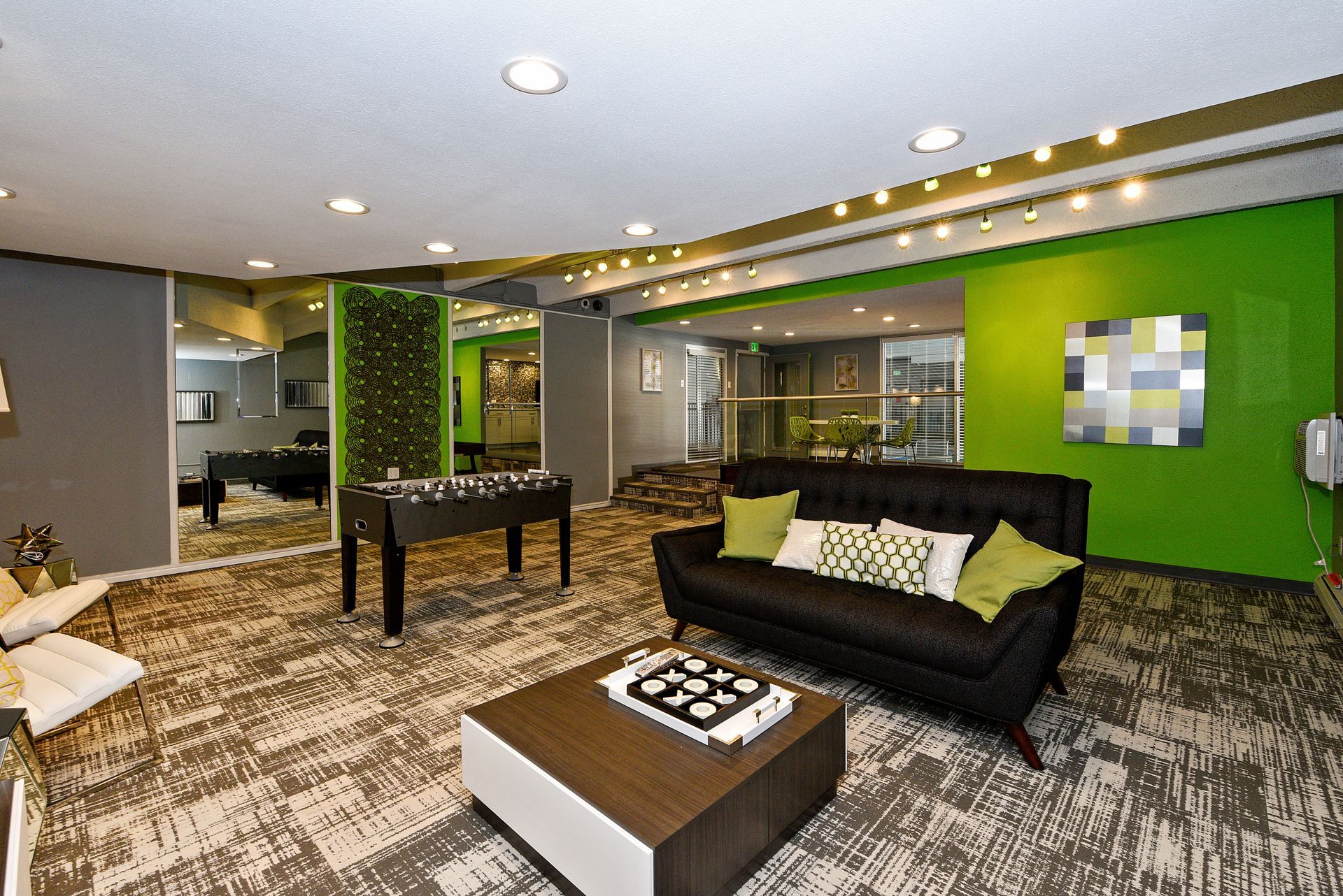 Modern lounge with black sofa, coffee tables, patterned carpet, and bright green accent wall