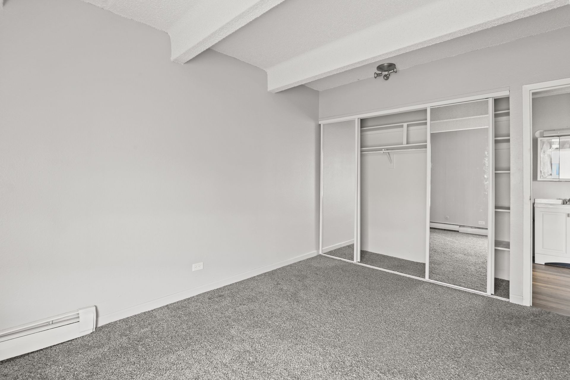 Empty carpeted bedroom with open closet and slanted ceiling