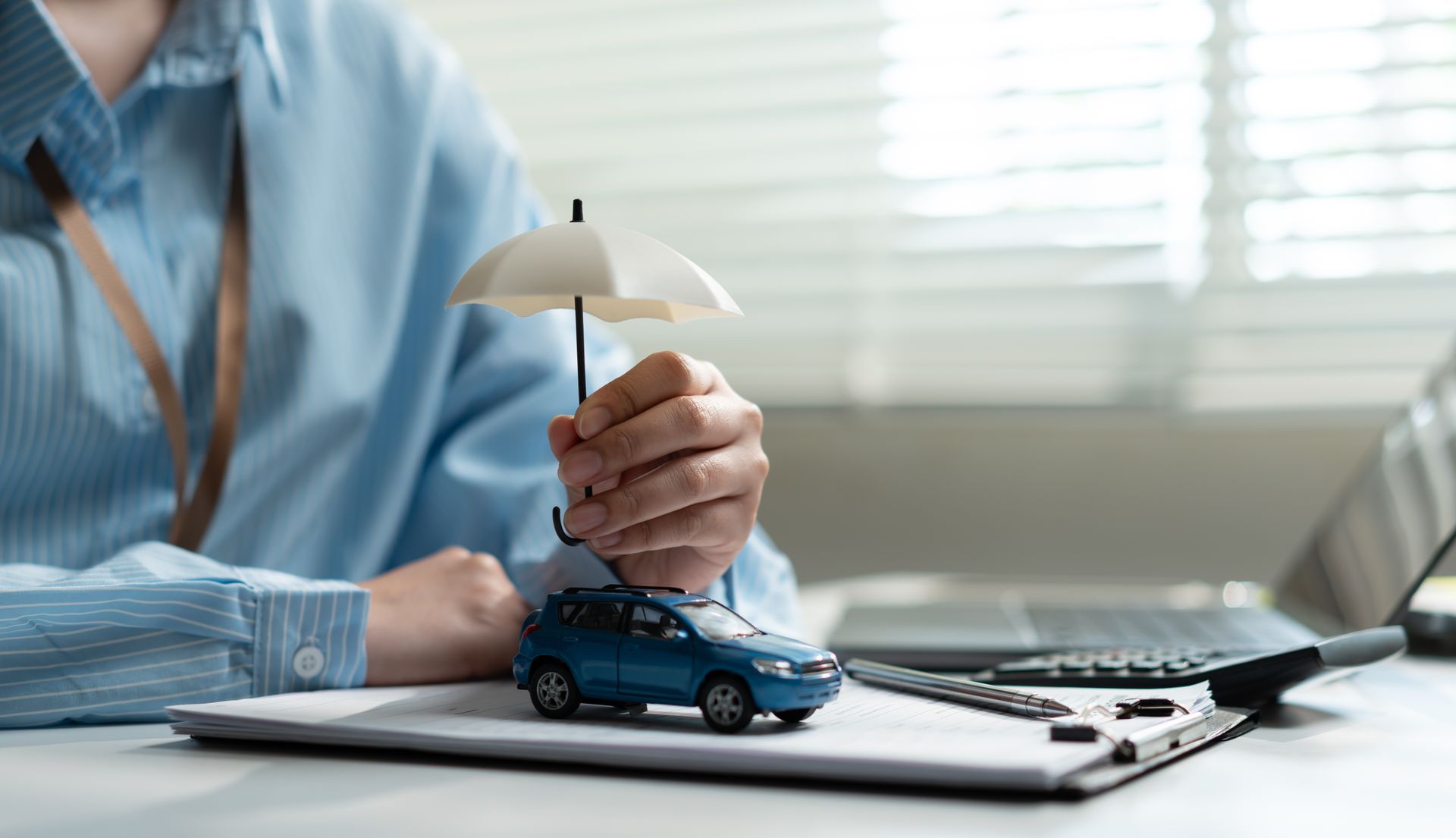 Toy car protected by umbrella symbolizing auto insurance coverage