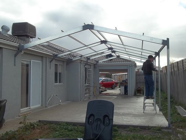 A man is standing on a ladder in front of a garage.