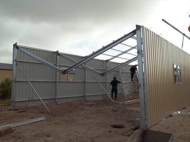 A man standing on a ladder in front of a building under construction
