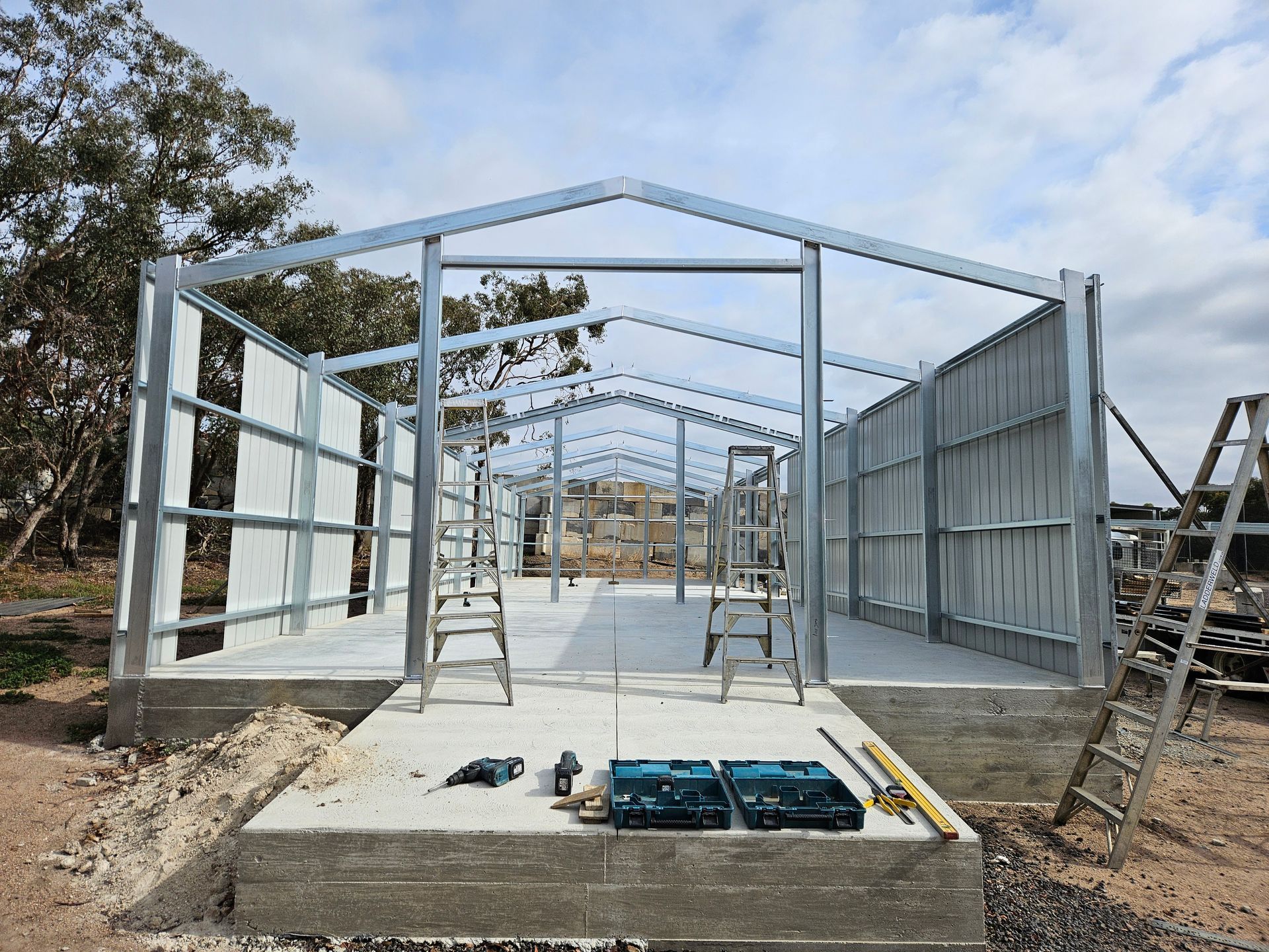 A large metal structure is being built on a dirt field.