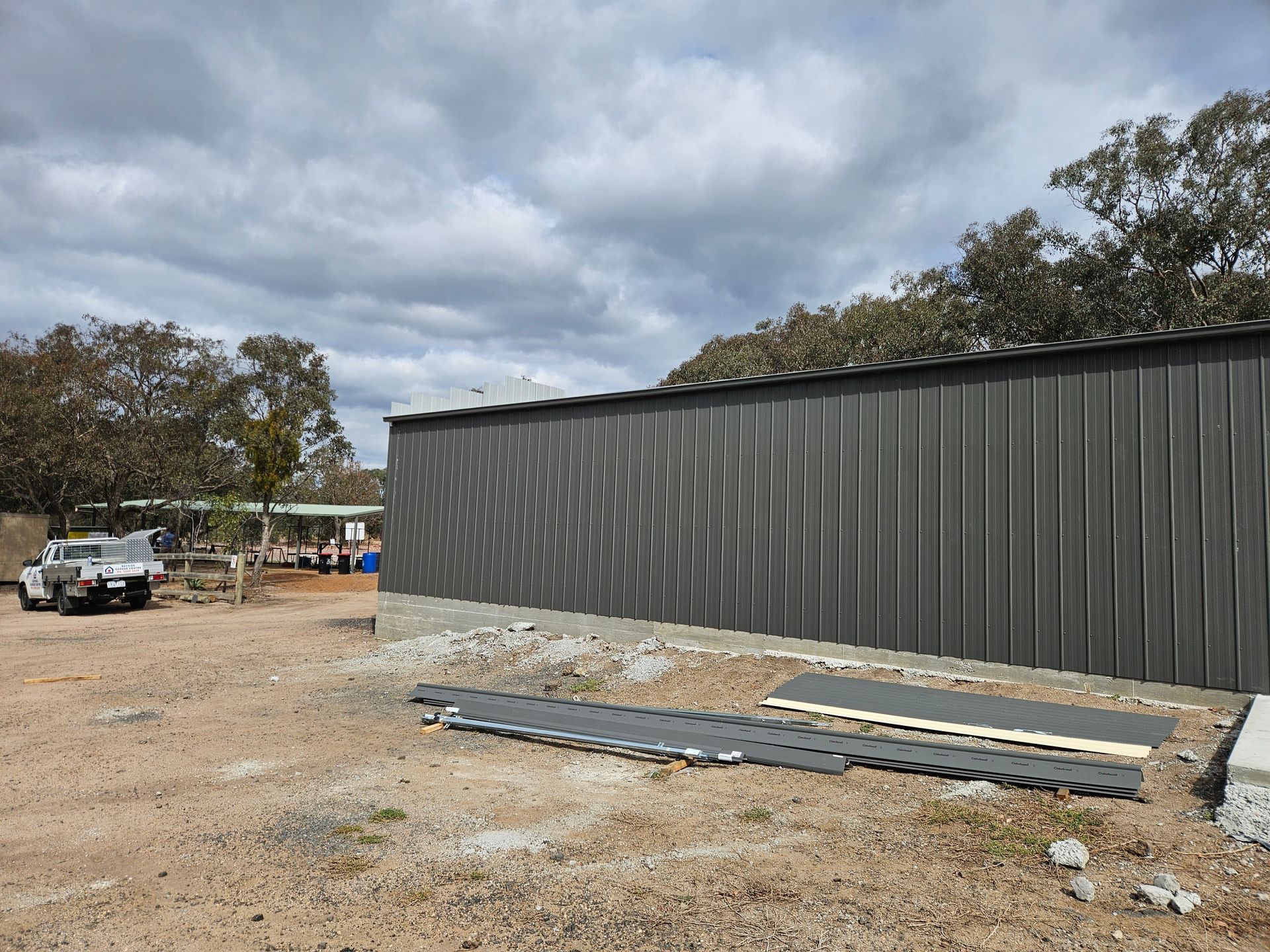 A large metal building is being built in a dirt field.