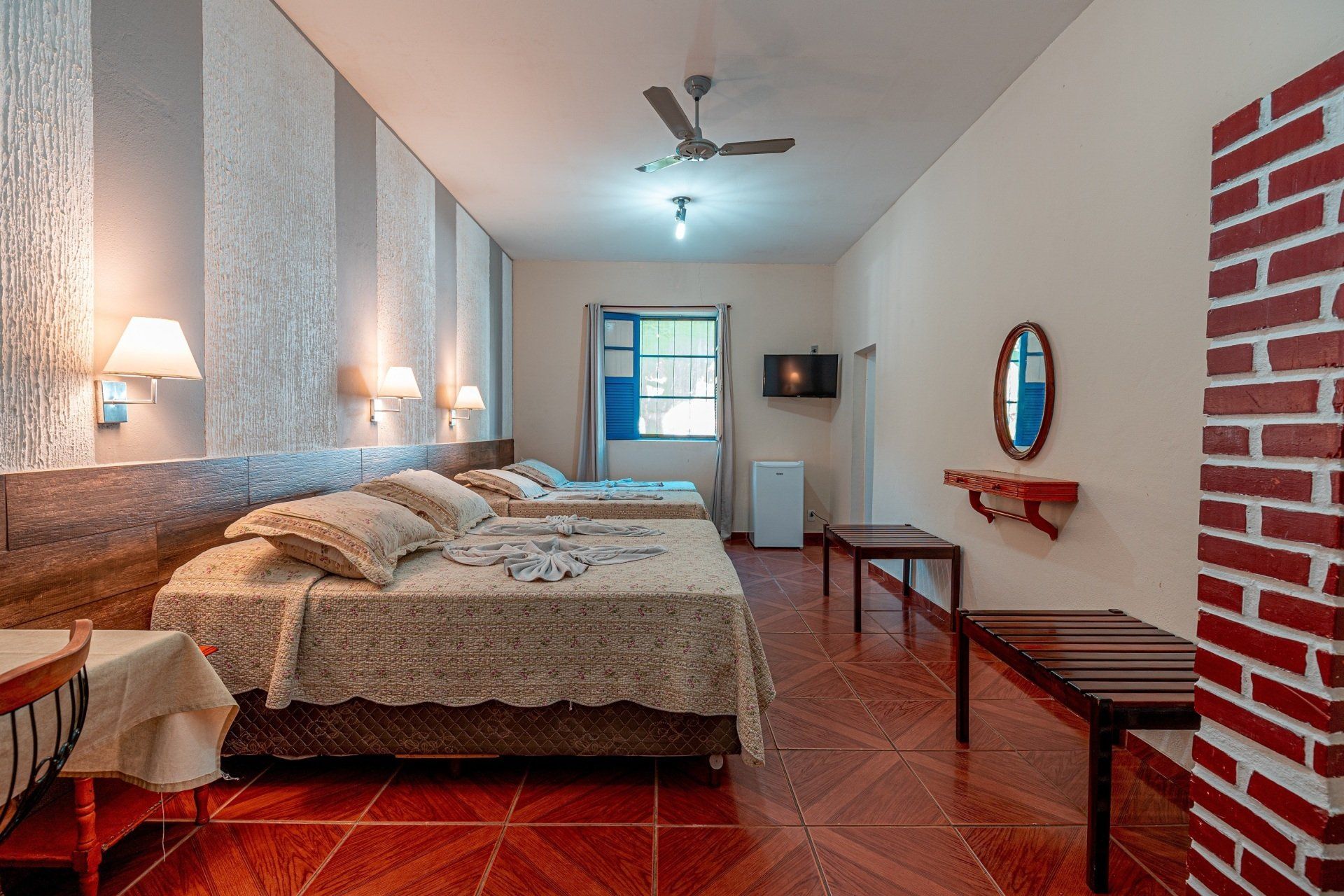 Quarto do Hotel Fazenda Santa Bárbara com camas de casal e parede de tijolinho