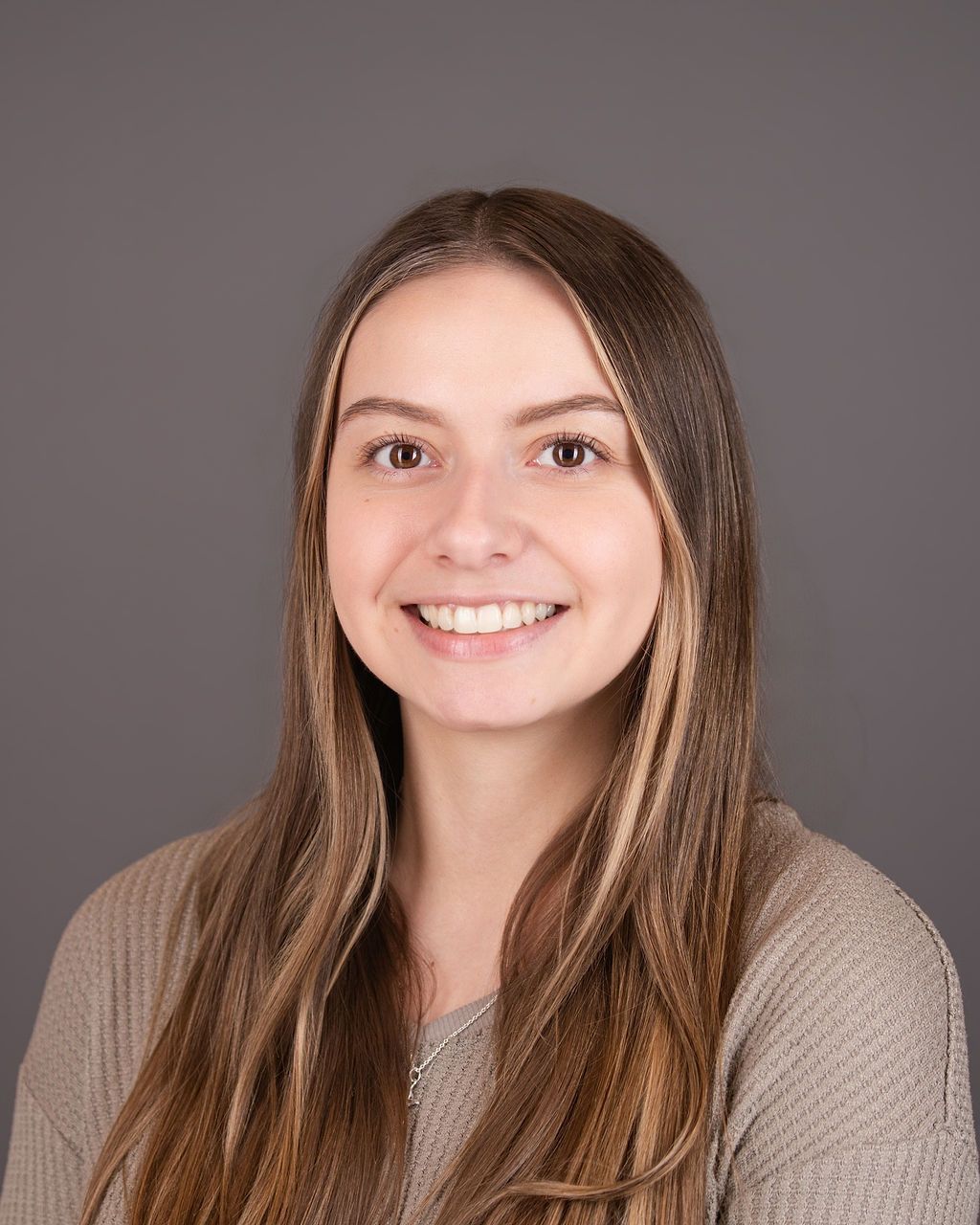 A woman in a tan blouse smiling in a professional headshot
