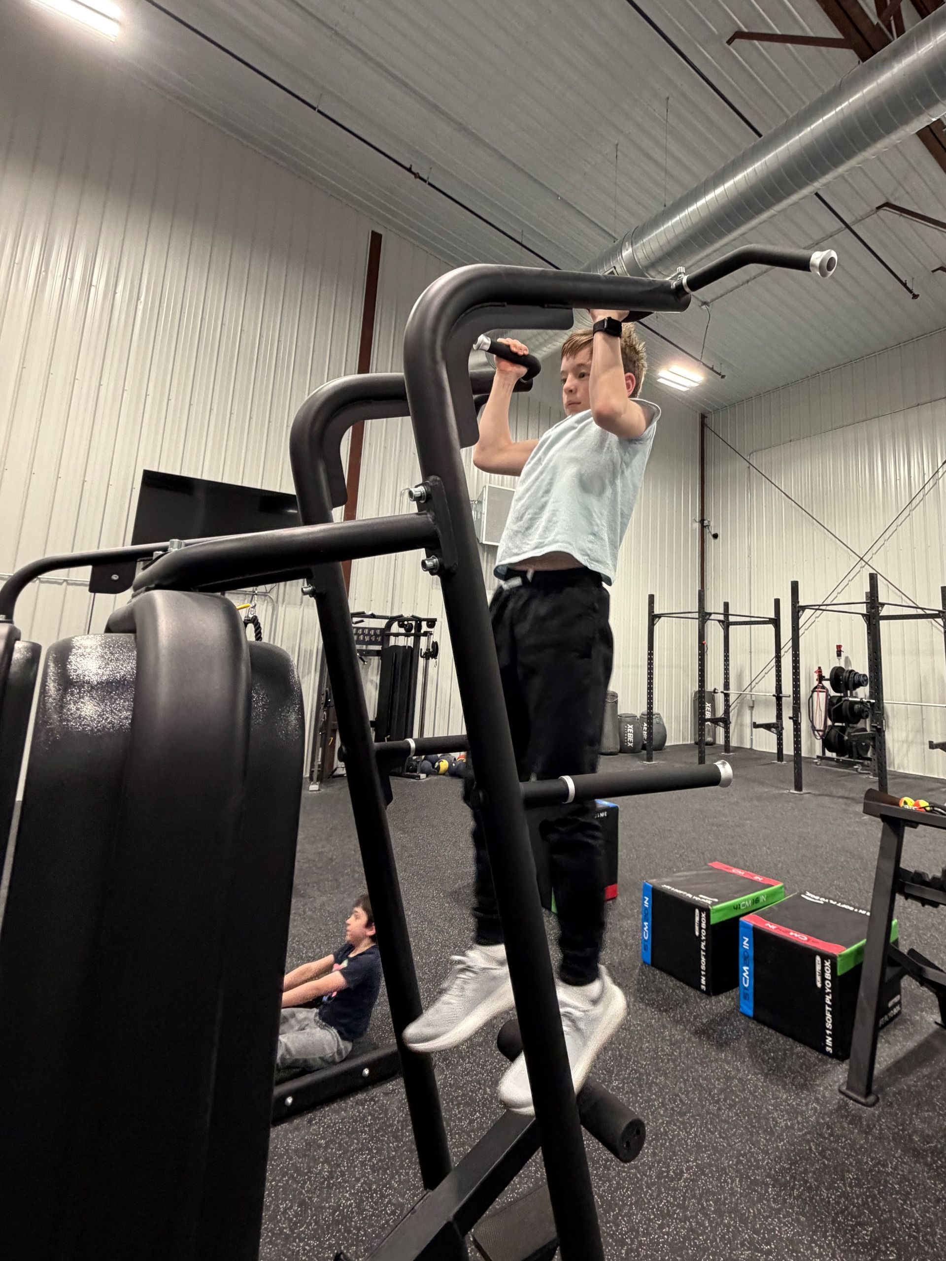 Child in red shirt using an elliptical machine in a gym