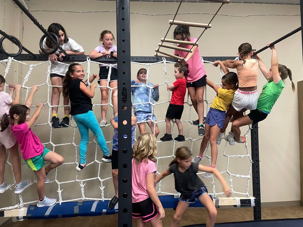 Children climbing a rope obstacle course indoors, hanging and balancing on ropes and bars