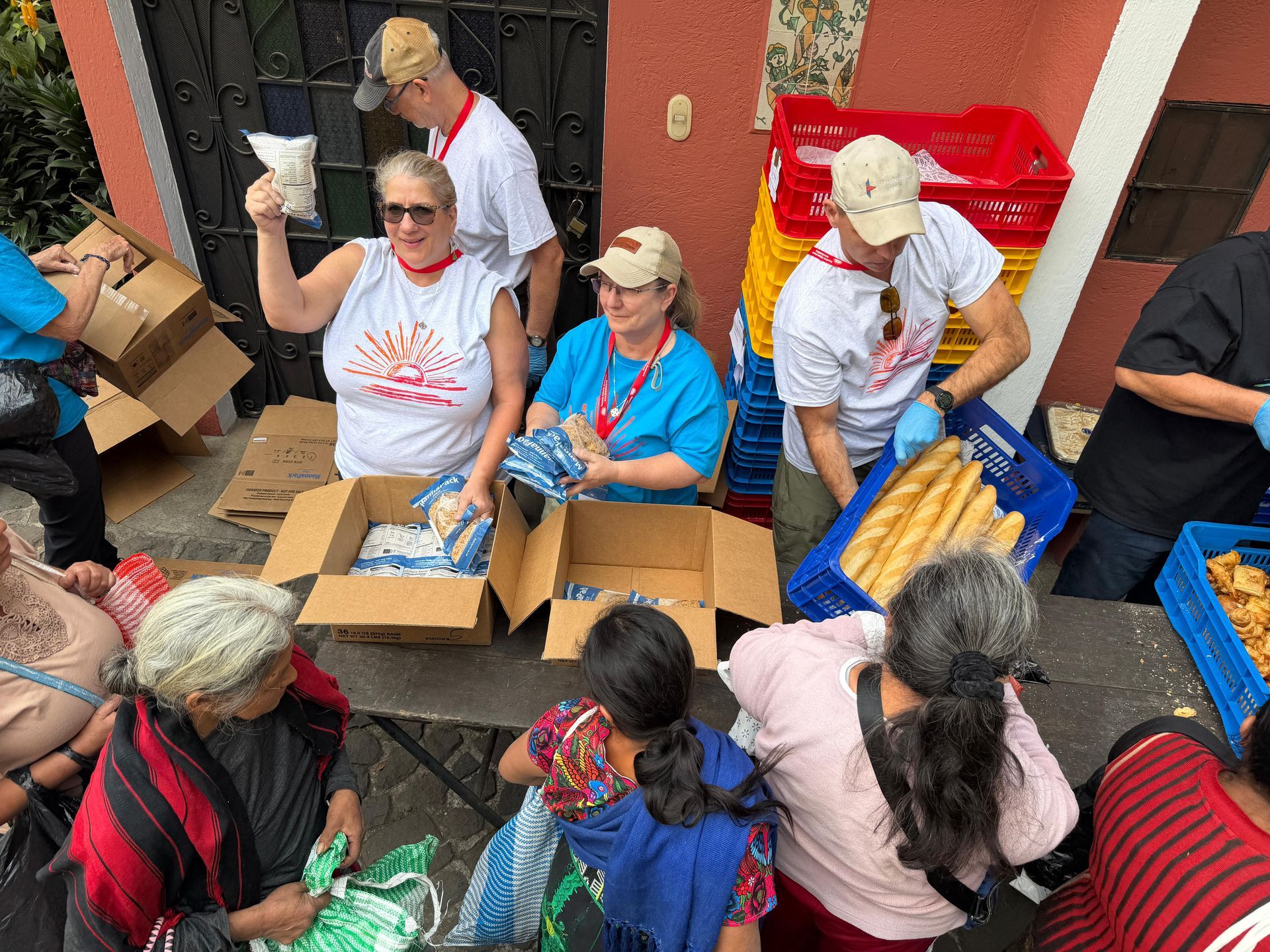 Volunteers distribute bread and supplies from boxes at an outdoor food donation event.