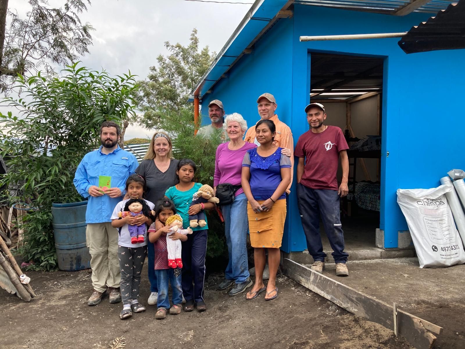 A group of people are posing for a picture in front of a blue building.