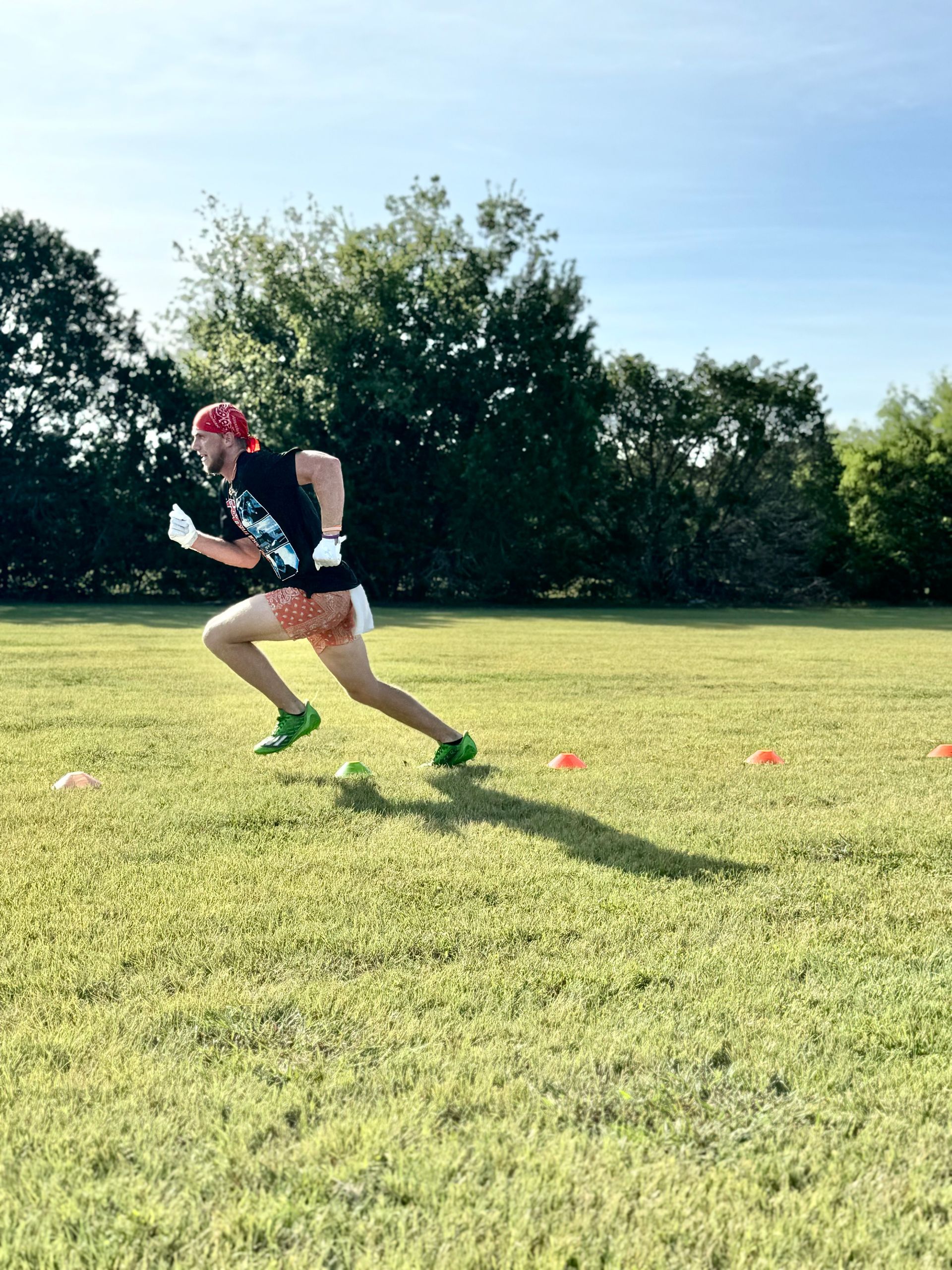 Person sprinting across a grassy field under a sunny sky.