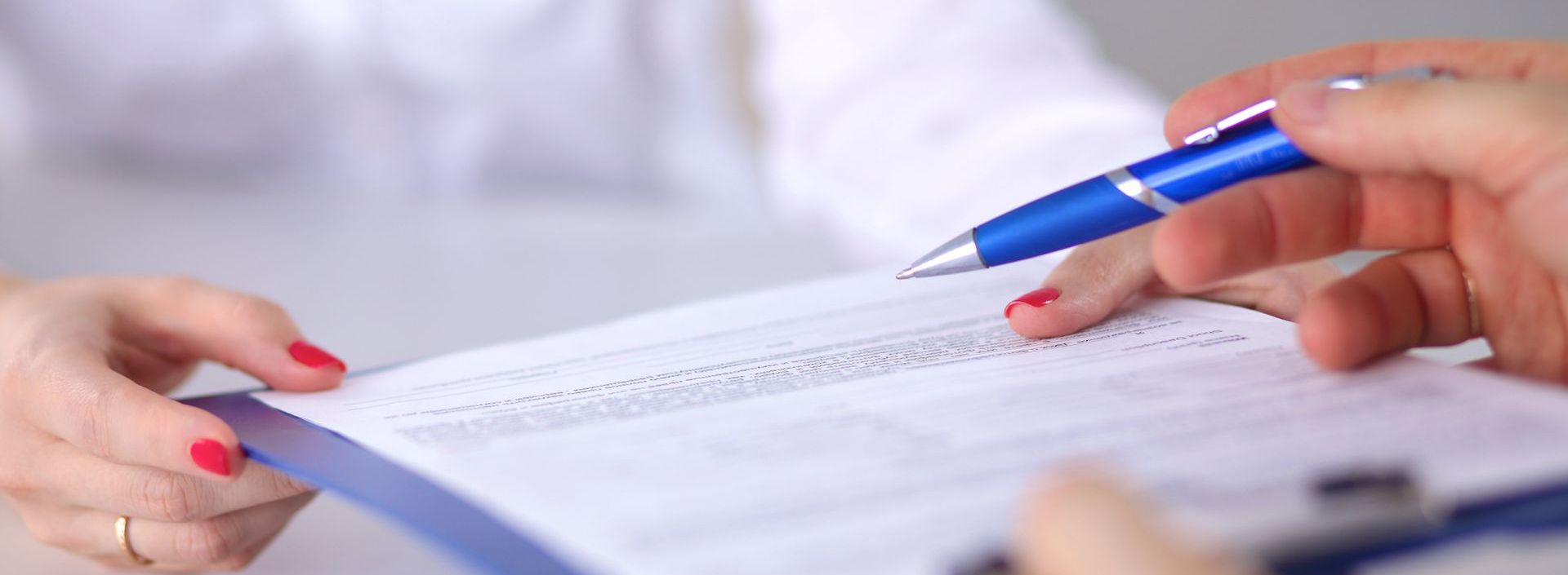 A woman is holding a pen over a clipboard.
