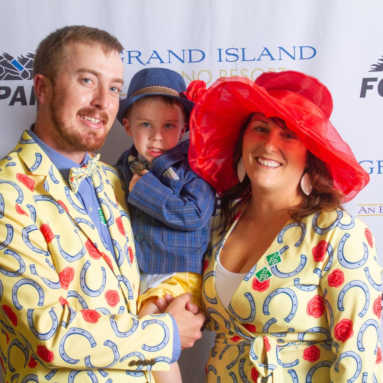 A man and woman holding a child in front of a sign that says grand island