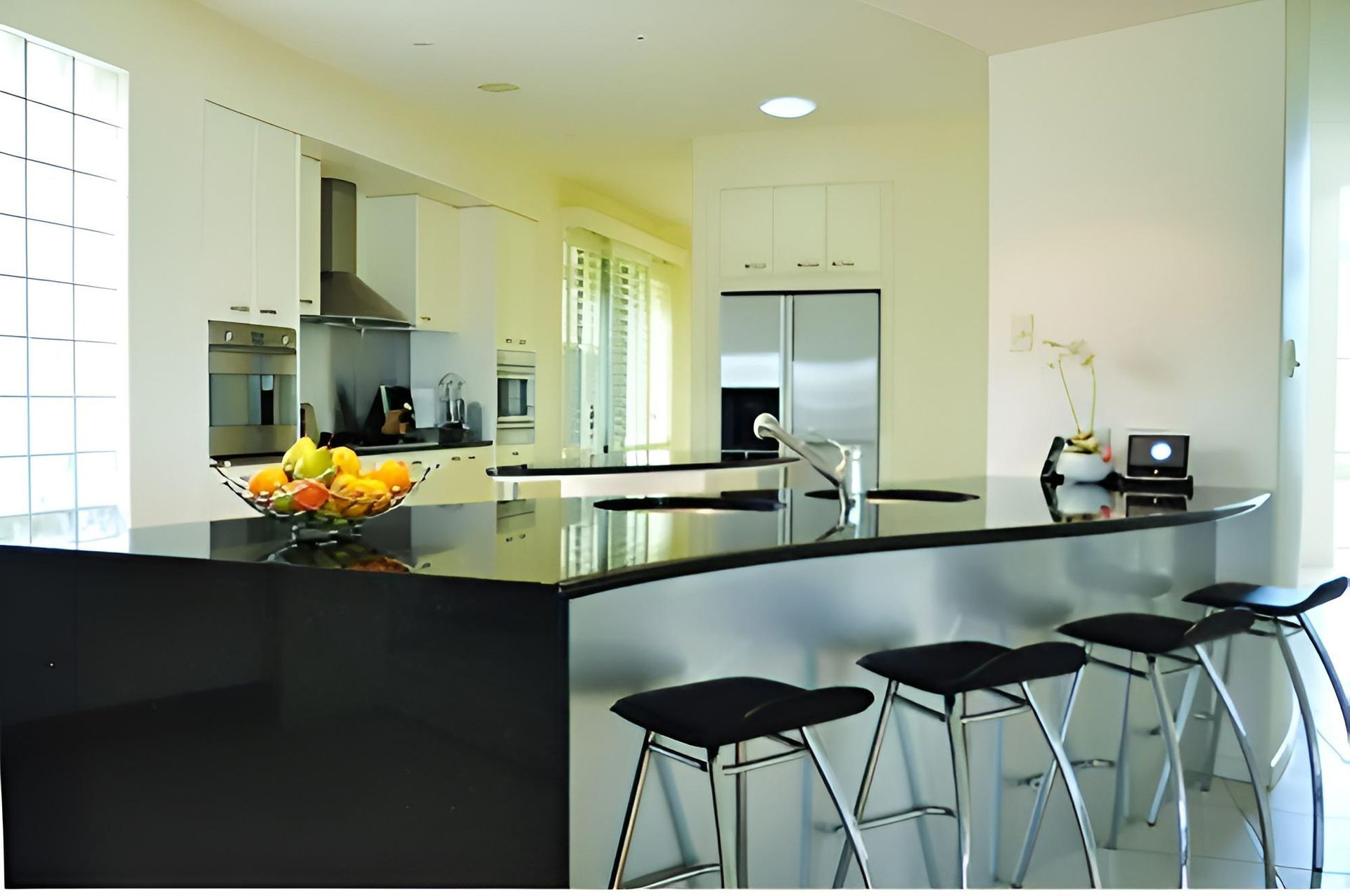 Kitchen With Black Counter Tops and Stools and a Bowl of Fruit on the Counter — Advance Kitchens in Caloundra West, QLD