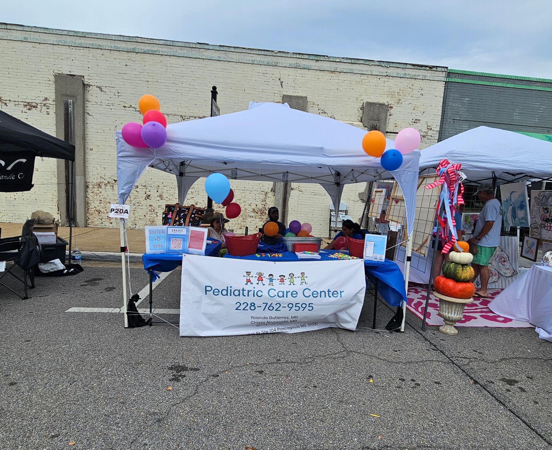 A white tent at an outdoor event with a banner that reads 
