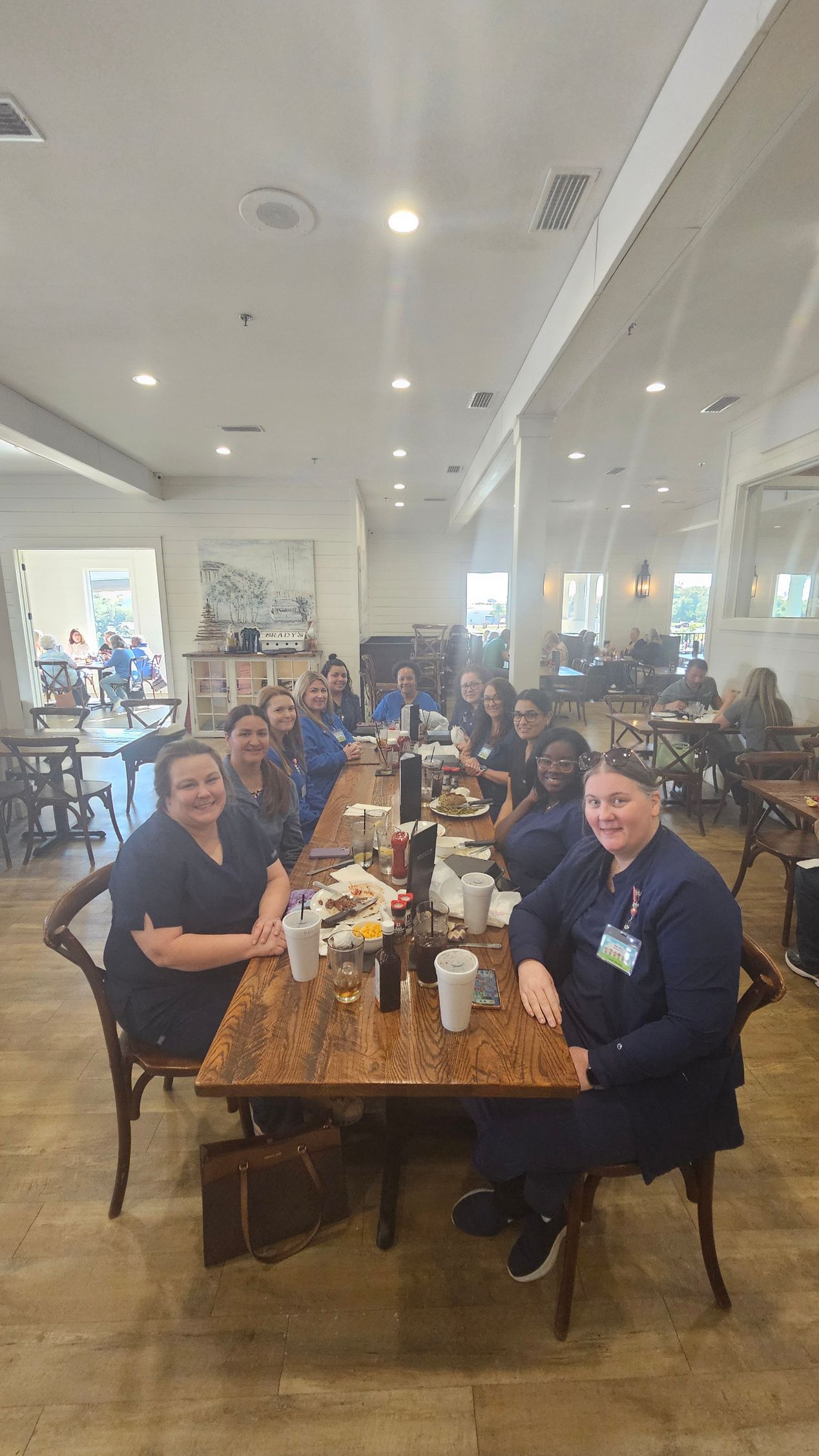 Group of people in blue uniforms seated at a long table in a restaurant.
