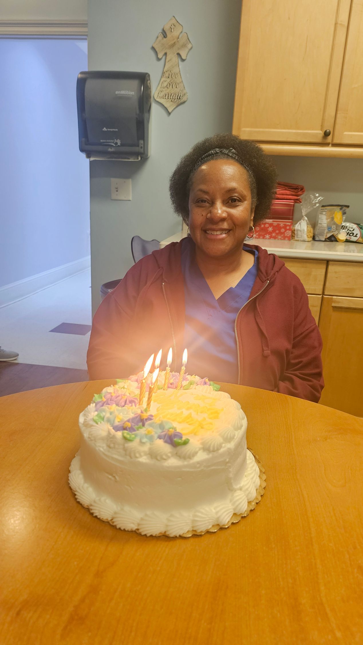 Woman smiling at birthday cake with lit candles.