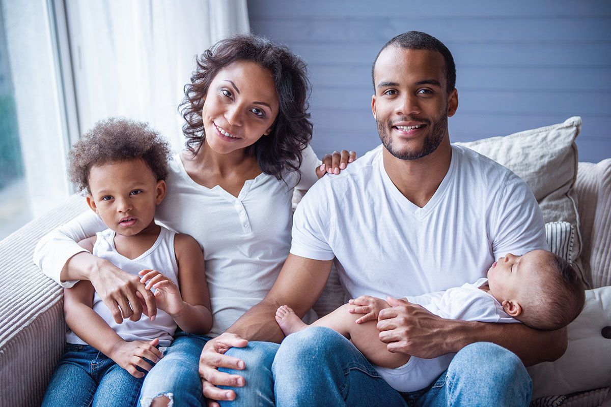 Family sitting together on a couch, smiling in a bright living room.