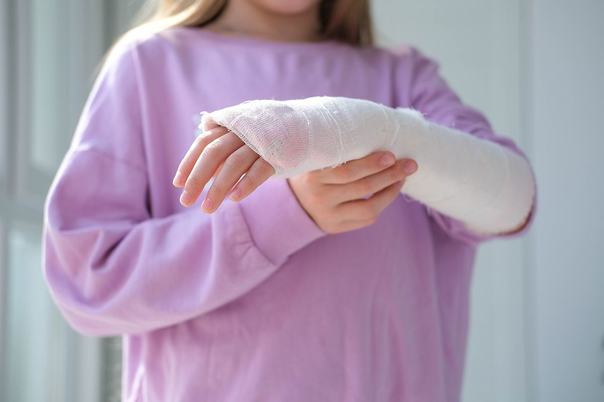 Person in a lavender sweatshirt with a white cast on their arm