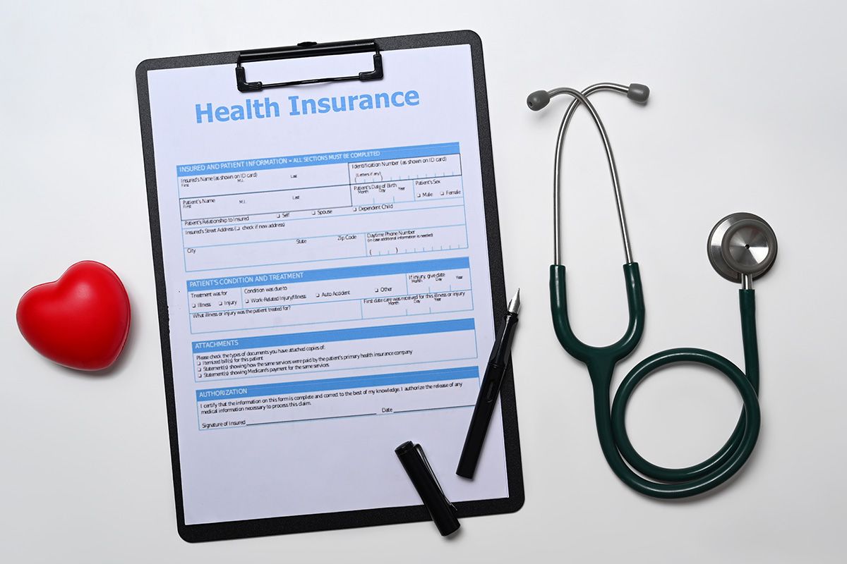 Health insurance form with stethoscope, pen, and red heart on white background