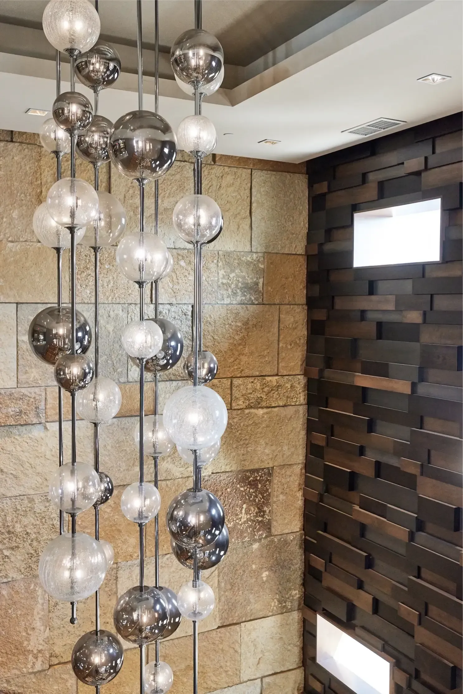 Interior lobby with a chandelier of glass globe orbs against stone and wood walls at The Walkway, which offers Minneapolis apartments for rent.