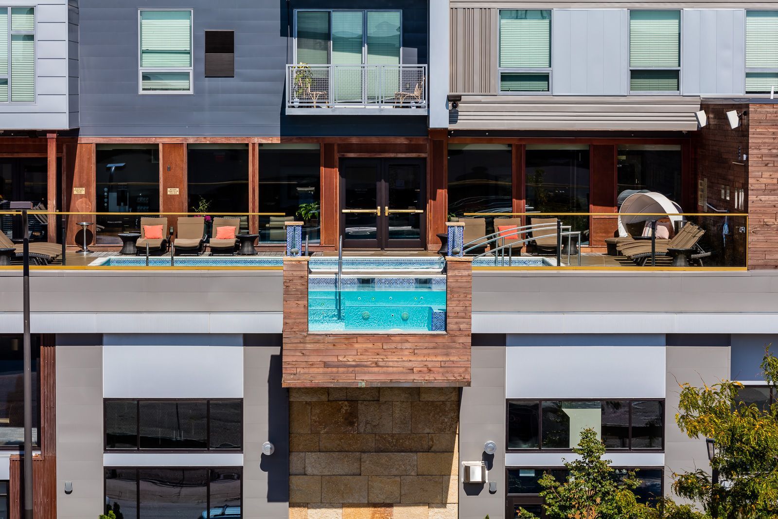 Exterior view of a modern apartment building with an outdoor pool and lounge seating on a deck at The Walkway, which offers pet-friendly apartments in Minneapolis, MN.