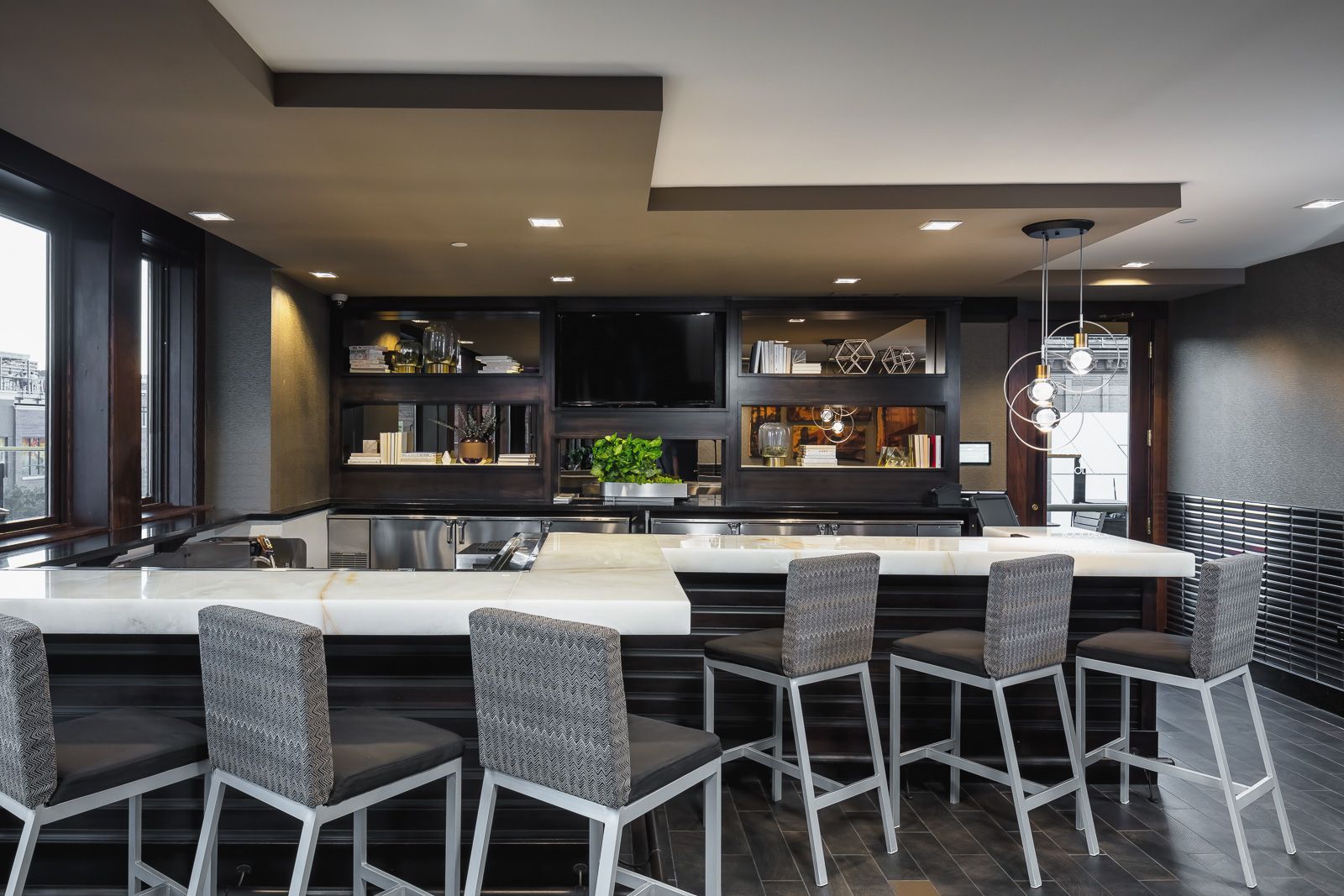 Modern communal bar area with a marble counter and tall upholstered stools at The Walkway, which offers apartments near downtown Minneapolis.