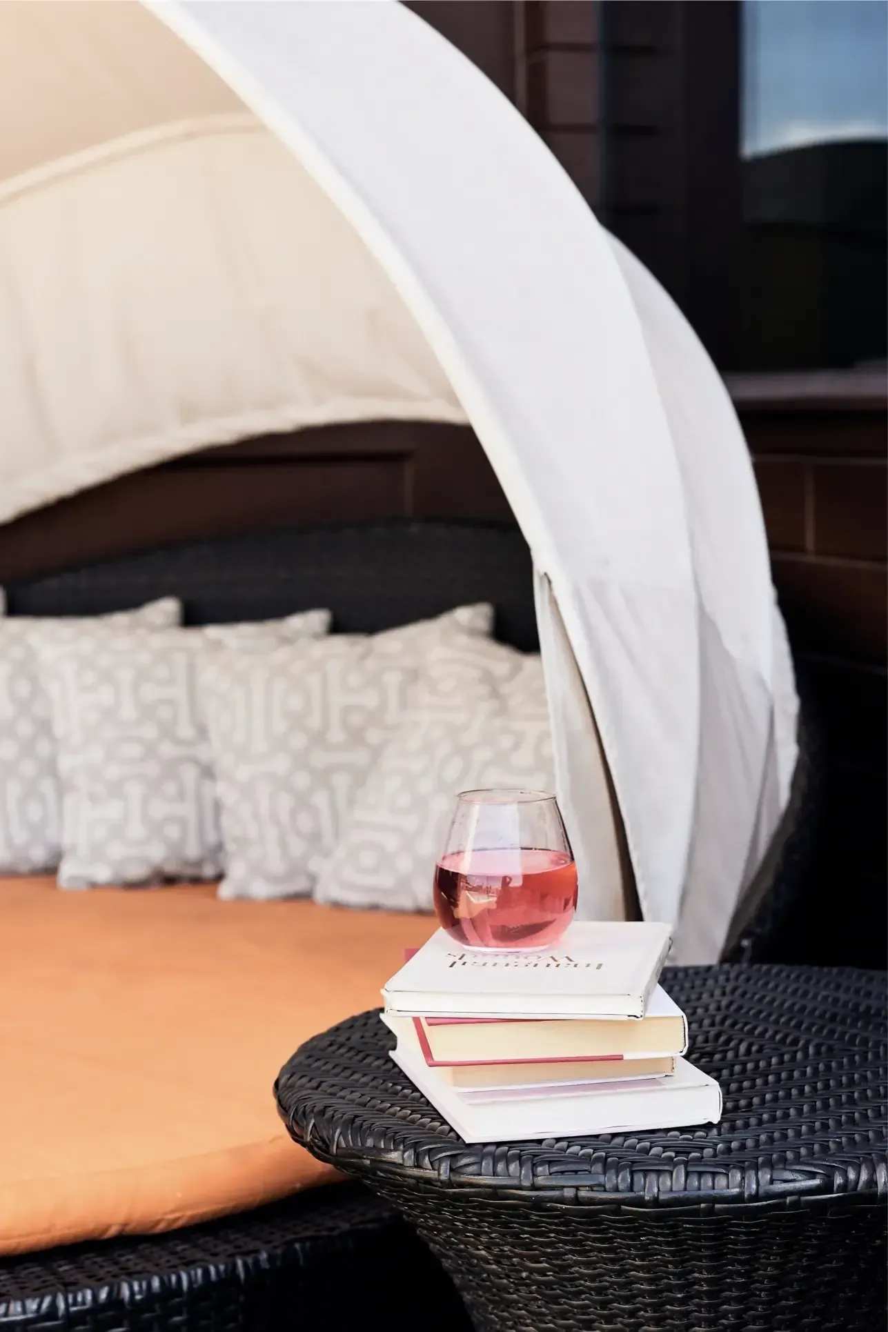 Outdoor community lounge with a white canopy, cushions, and a pink drink on a wicker table at The Walkway, which offers Minneapolis apartments for rent.