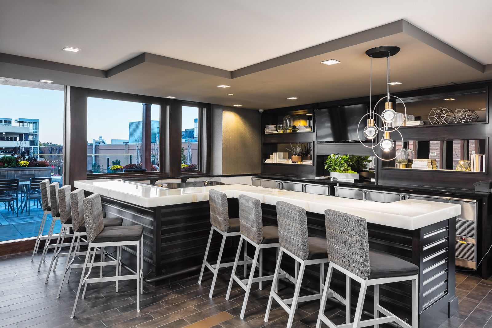 Modern community bar area with a marble-topped island, high chairs, and built-in shelving at The Walkway, which offers apartments near downtown Minneapolis.