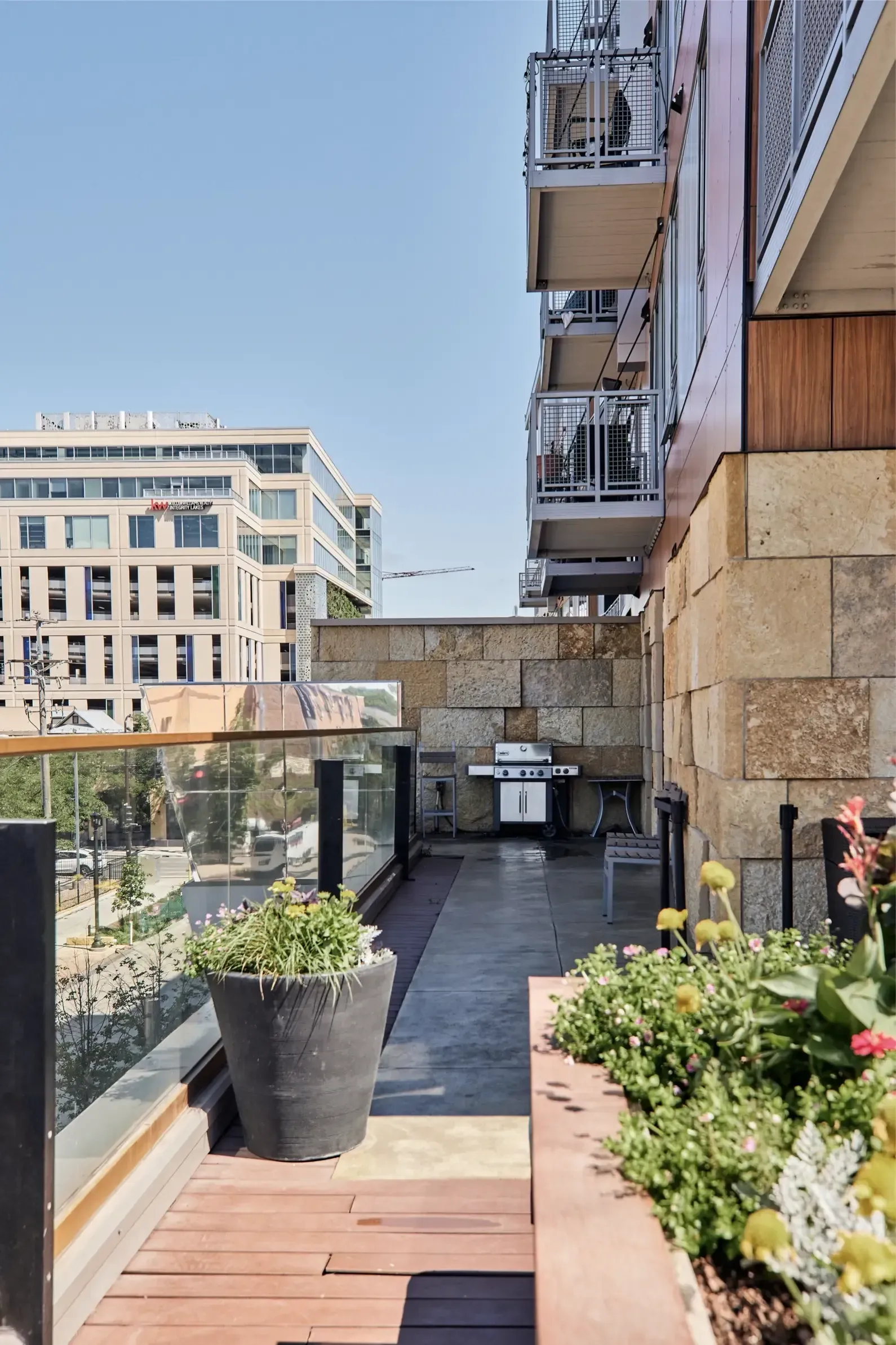 Balcony of an apartment with large planters and a grill, overlooking a city street at The Walkway, which offers apartments in Minneapolis, MN.