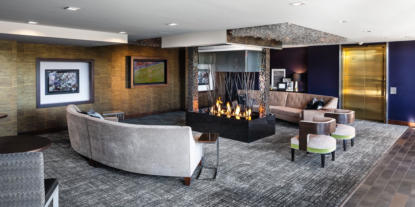 Modern residential lobby with sofas, a glass fireplace, artwork, and an elevator at The Walkway, which offers apartments in Uptown Minneapolis, MN.