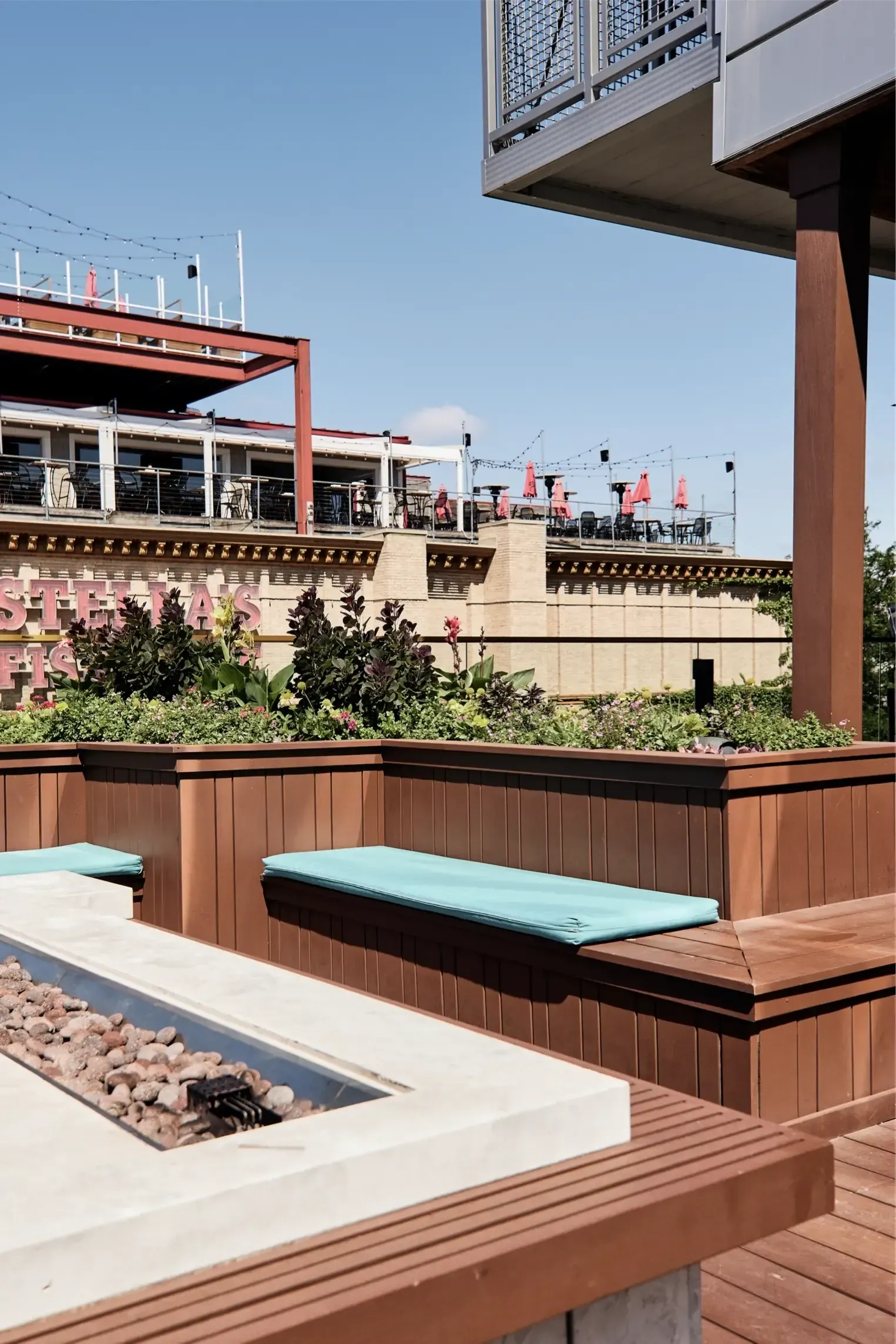 Rooftop outdoor lounge with wooden benches, planters, and a fire pit at The Walkway, which offers apartments in Minneapolis, MN.