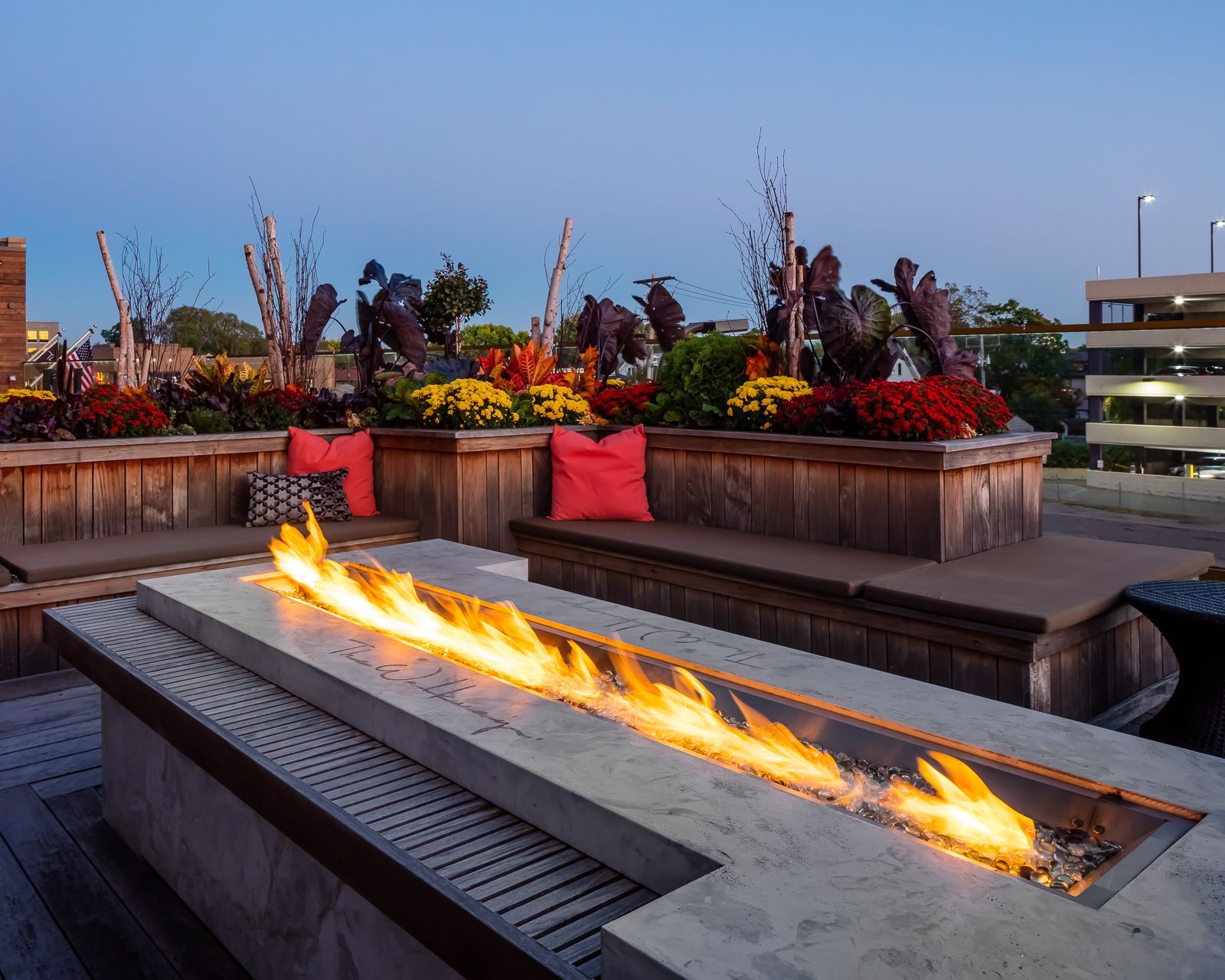 Outdoor rooftop lounge with a long fire pit, built-in benches, and colorful planters at The Walkway, which offers apartments for rent in Minneapolis, MN.
