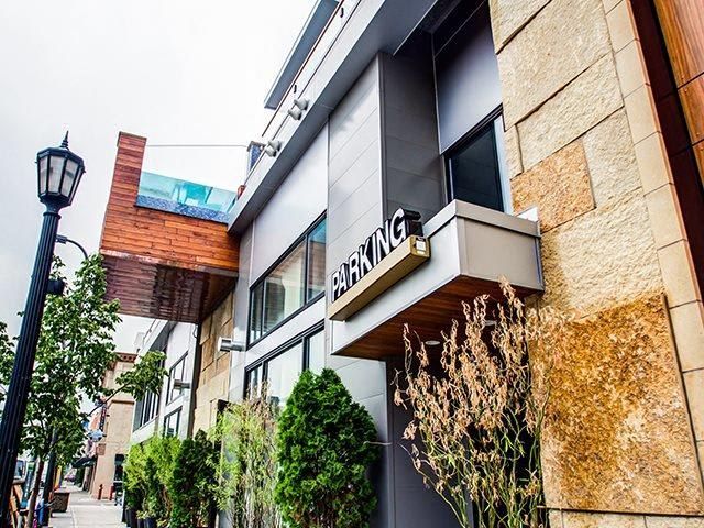 Exterior view of a modern apartment building with a parking sign and greenery at The Walkway, which offers apartments in Minneapolis, MN.