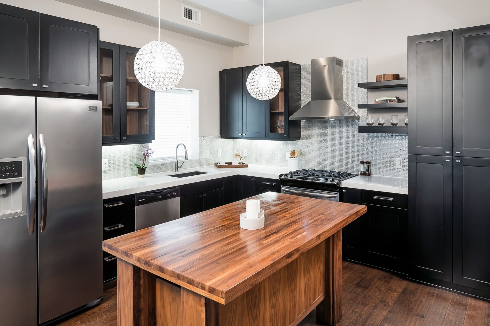 Modern kitchen with black cabinets, stainless steel appliances, and a large wooden island at The Walkway, which offers apartments in Uptown Minneapolis, MN.