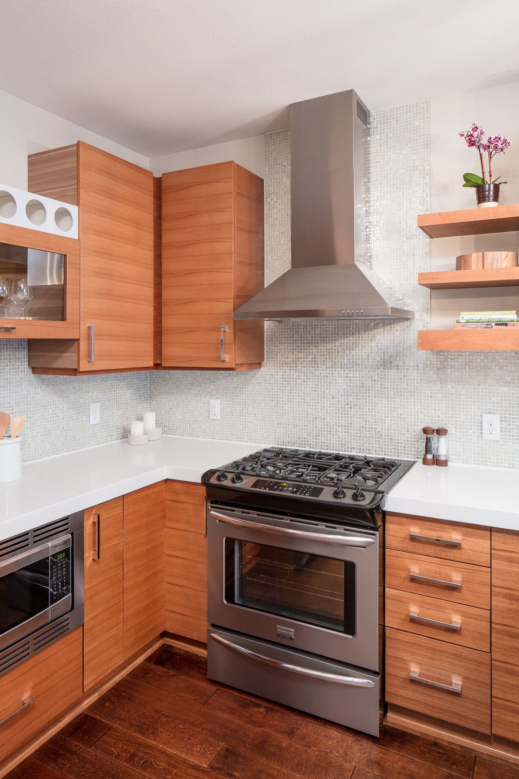 Modern apartment kitchen with stainless steel stove, vent hood, and wood cabinets at The Walkway, which offers apartments in Uptown Minneapolis, MN.