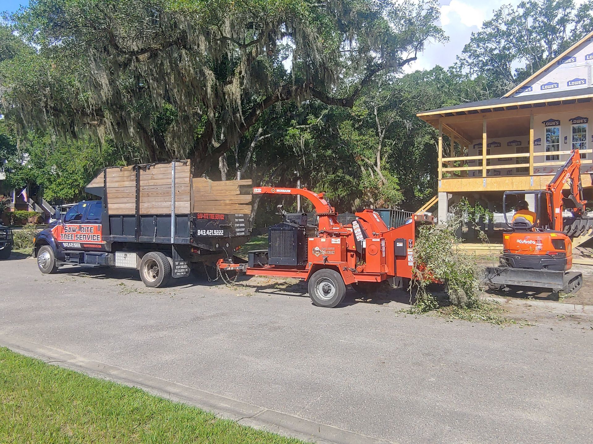 A truck and a tree chipper are parked in front of a house.