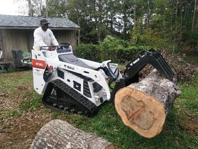 A man is driving a bulldozer next to a large log.