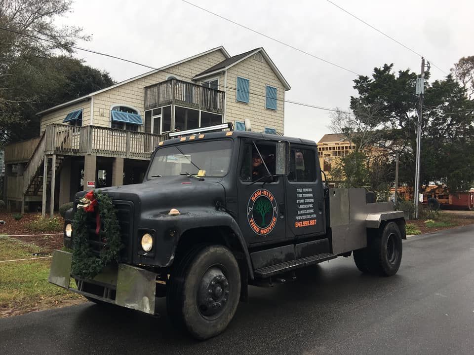 A black truck is driving down a street in front of a house.