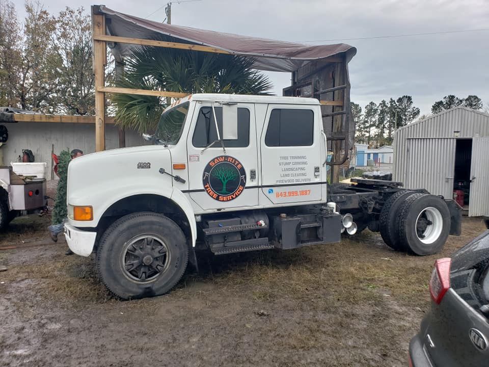 A white semi truck is parked in a muddy field next to a shed.