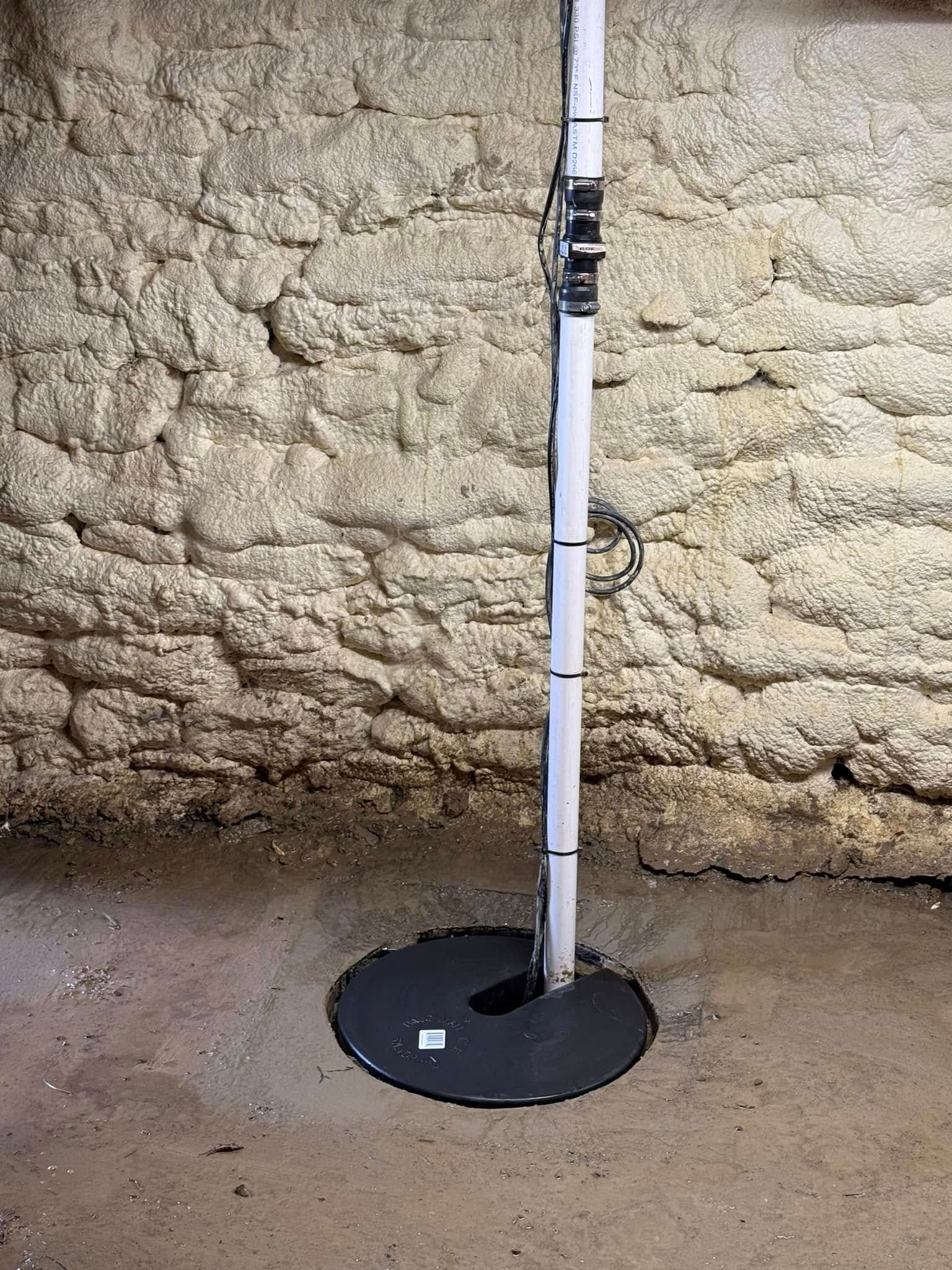 White pole mounted on a black circular base against a rough tan wall.