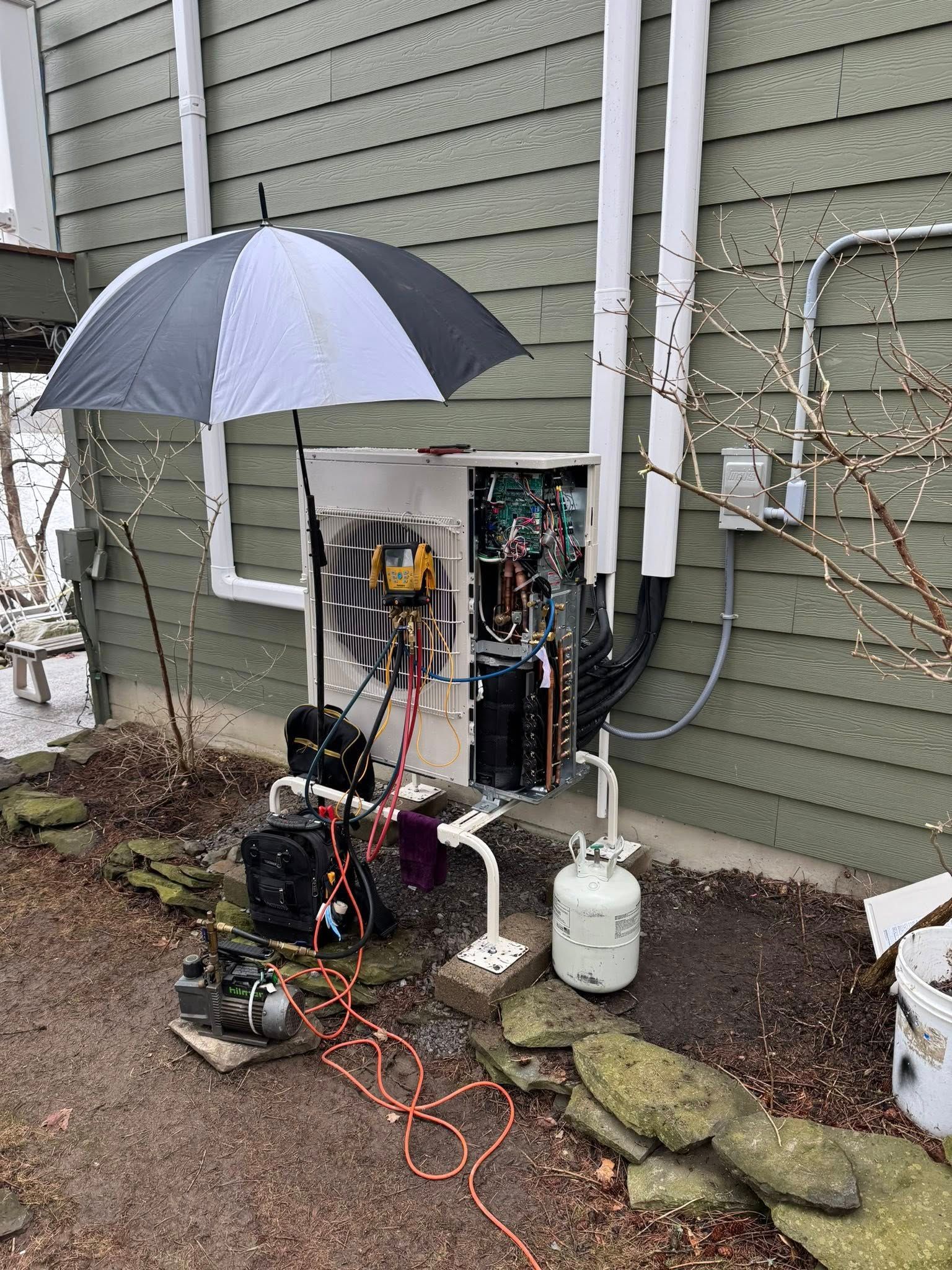 Outdoor electrical setup with umbrella cover, wires, and equipment against a house wall