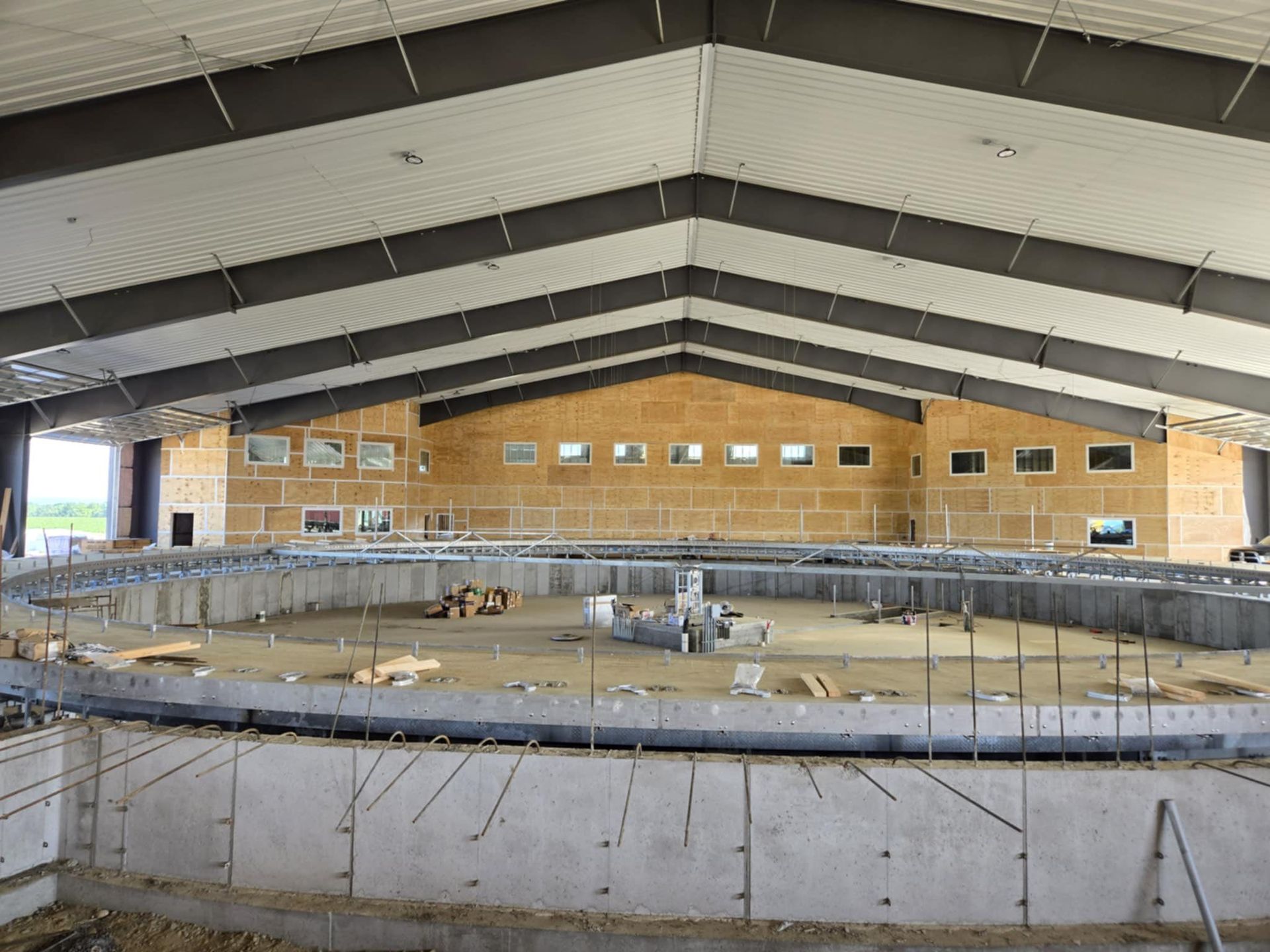 Indoor swimming pool under construction inside a large arched building, with empty lanes and scaffolding.