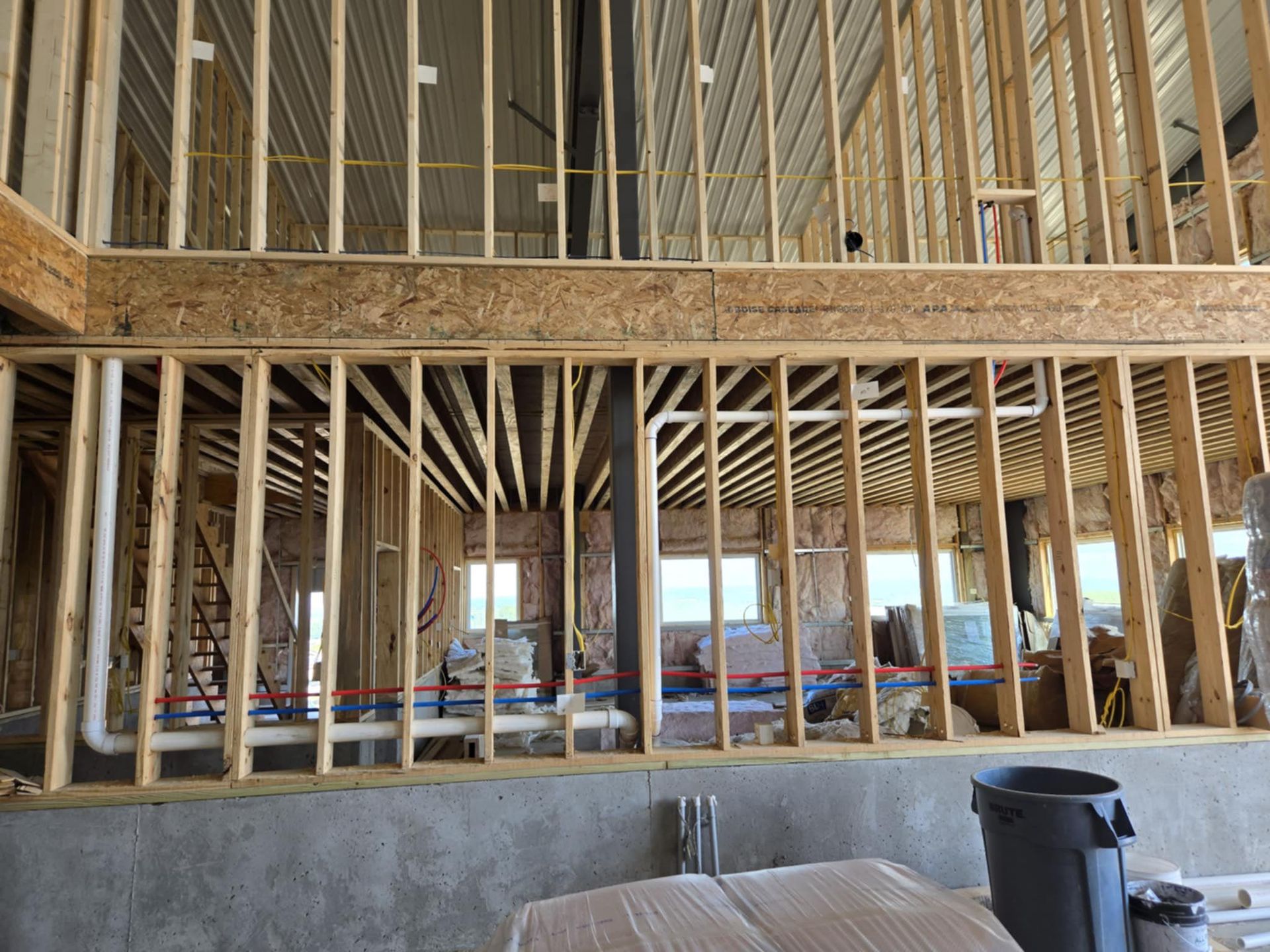 Interior of a house under construction with exposed wooden framing and a concrete foundation wall