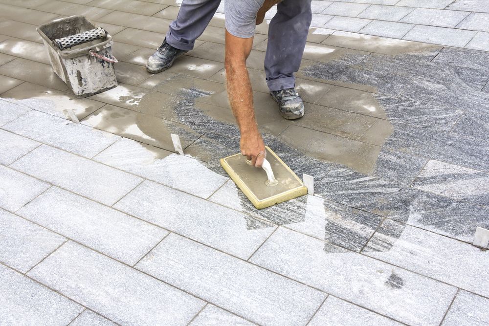Man Laying Grey Tiles Outdoors — Maestro Tiling Services In Murrumbateman, NSW