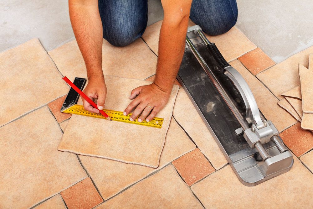 A Man is Measuring a Tile With a Ruler and Pencil — Maestro Tiling Services In Murrumbateman, NSW