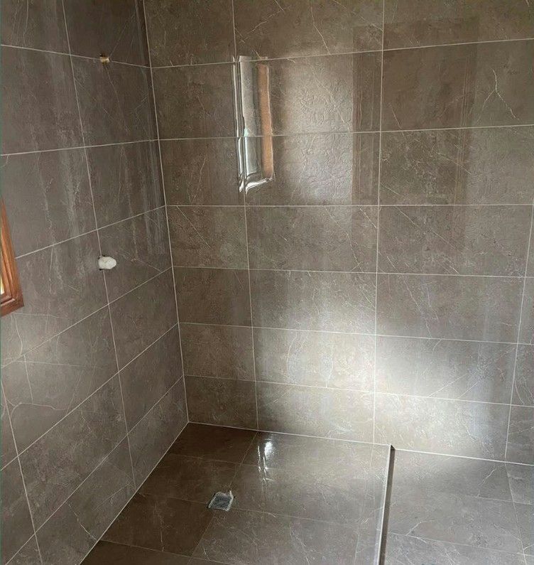 A Bathroom With Tiled Walls and a Walk in Shower With a Glass Door — Maestro Tiling Services In Latham, ACT