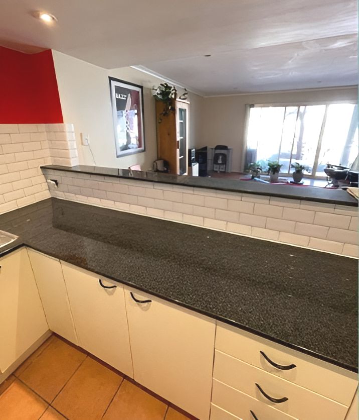 A Kitchen With Black Granite Counter Tops and White Cabinets — Maestro Tiling Services In Latham, ACT