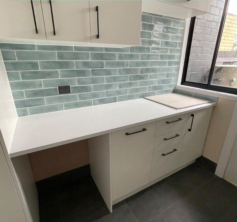 A Kitchen With White Cabinets and Blue Tiles on the Wall — Maestro Tiling Services In Latham, ACT